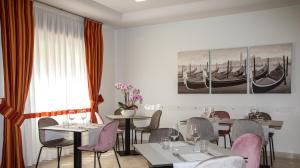 um restaurante com mesas e cadeiras e uma pintura de barcos em Hotel Imperia em Lido di Jesolo
