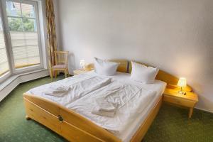 um quarto com uma cama grande com lençóis brancos e almofadas em An der Galerie, B 02 em Zingst