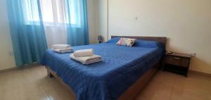a bedroom with a blue bed with towels on it at Vasilas Holiday Apartment #1 in Larnaka +29 photos