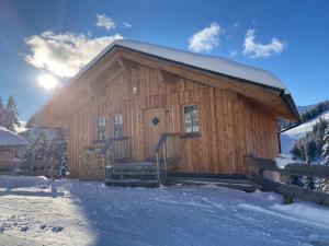 a log cabin in the snow with the sun behind it at Jagdhütte in Lachtal