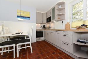 a kitchen with white cabinets and a table and a counter at Haus Bornholm Whg 04 in Nieblum