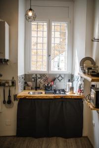 uma cozinha com um balcão com um lavatório e duas janelas em Umbrian Concierge - Factory House La Viola em Perugia