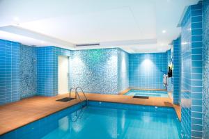 La salle de bains est pourvue d'une piscine avec du carrelage bleu. dans l'établissement Swiss Blue Hotel Hera, à Djeddah
