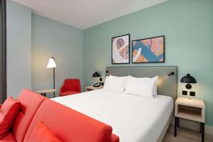 a bedroom with a white bed and a red couch at Hyatt Place London City East in London