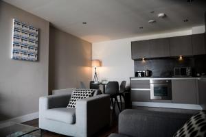 a living room with a couch chair and a kitchen at OnPoint - Spacious 2 Bedroom Apt, City Centre With Balcony in Manchester