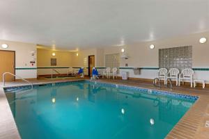 a pool in a hotel with chairs and tables at Comfort Inn South-Medford in Medford