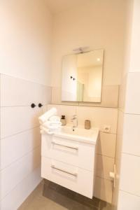 W białej łazience znajduje się umywalka i lustro. w obiekcie Apartment No1 w mieście Stralsund