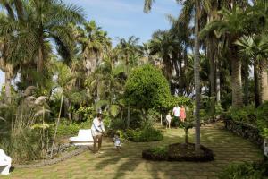 プエルト・デ・ラ・クルスにあるApartment 327 im Precise Resort Tenerifeの椰子の木が生える公園を歩く女子