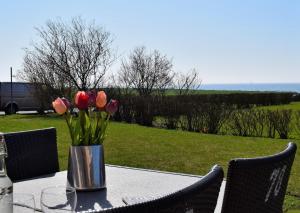 a vase of tulips on a table with a view of a field at Fehmarnstrand 78 App 9 in Staberdorf