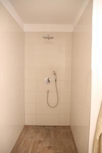 eine Dusche in einem Zimmer mit weißen Fliesen in der Unterkunft Casa Kronengarten Nr 1 in Hilden