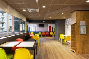 a dining room with tables and yellow chairs at Ibis Budget Bourgoin Jallieu Centre in Bourgoin