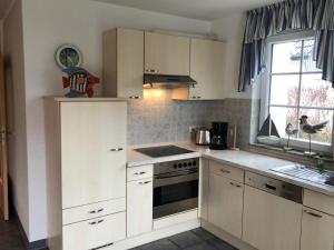 a kitchen with white cabinets and a stove and a window at Strandmuschel - a05355 in Zingst