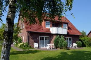 a red brick house with a white balcony and a table at Ferienwohnungen Seeburger Weg in Carolinensiel