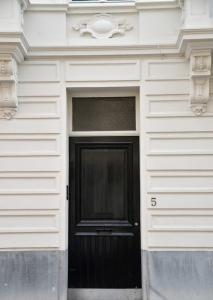 eine schwarze Tür an der Seite eines weißen Gebäudes in der Unterkunft Chantilly Townhouse in Gent