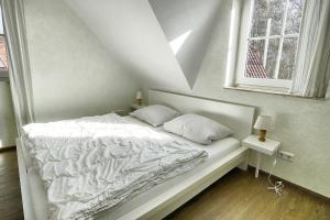 - un lit blanc avec deux oreillers et une fenêtre dans l'établissement Am Deich 47, à Zingst