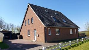 une grande maison en briques avec un toit noir dans l'établissement Haus Michel, à Nordstrand