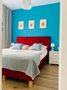 1 dormitorio con cama roja y pared azul en Apartament Walczaka 15 MIEJSCE PARKINGOWE, en Gorzów Wielkopolski
