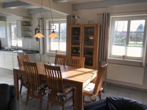 a kitchen with a wooden dining room table and chairs at Osterharde in Wrixum