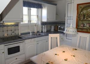 a kitchen with white cabinets and a sink at Ferien unterm Reetdach Whg 03 in Oevenum