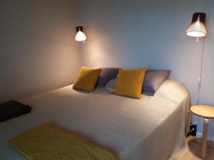 una camera da letto con un letto con cuscini gialli e due luci di Graniitti a Hanko