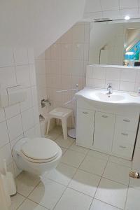 a white bathroom with a toilet and a sink at Hennig, Otti in Zingst
