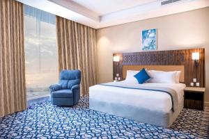 a hotel room with a bed and a chair at Swiss Blue Hotel Hera in Jeddah