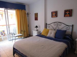 Un dormitorio con una cama con almohadas azules y amarillas. en Jardín Marino, en Puerto de Santiago 127 fotos más