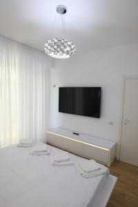 Habitación blanca con TV de pantalla plana en la pared en Nicho Residence 2 Bucurestii Noi en Bucarest