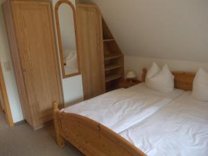 - une chambre avec un lit blanc et un miroir dans l'établissement Finnhäuser am Vogelpark - Haus Brizi, à Marlow