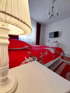 a bedroom with a red bed and a table with a lamp at 2 rooms apartment Telecabinei Busteni in Buşteni
