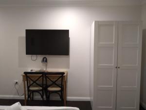 a bedroom with a desk and a television on a wall at Allonville Gardens Motel in Wagga Wagga