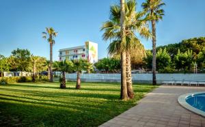 a park with palm trees and a building at Camping Bellsol Pets in Pineda de Mar