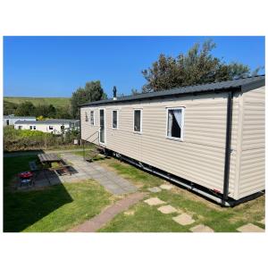 Hollington的住宿－Cosy 3-Bed Caravan combe haven st Leonards on sea，白色的小房子,配有野餐桌和长凳