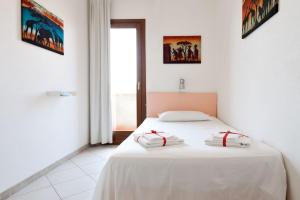 a bedroom with a white bed with two pillows on it at Granito's in Monte Petrosu