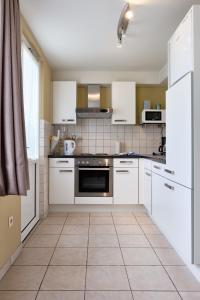 a kitchen with white appliances and a tile floor at Pieters Huis in Kinrooi