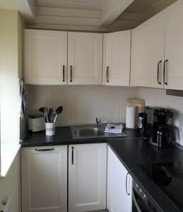uma cozinha com armários brancos e um lavatório em Soling em Laboe