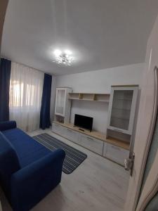 a living room with a blue couch and a television at 2 rooms apartment Telecabinei Busteni in Buşteni