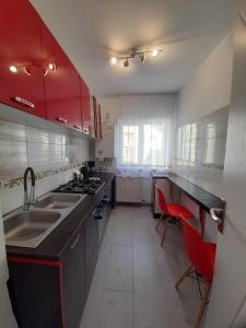 a kitchen with red cabinets and a sink and red chairs at 2 rooms apartment Telecabinei Busteni in Buşteni