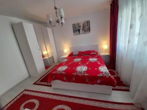 a red bed with red pillows in a white bedroom at 2 rooms apartment Telecabinei Busteni in Buşteni