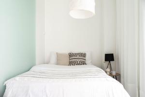 a white bedroom with a bed and a lamp at NEW stylish 2br apartment in the city center in Oulu