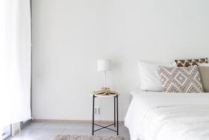 a bedroom with a white bed with a side table at NEW stylish 2br apartment in the city center in Oulu