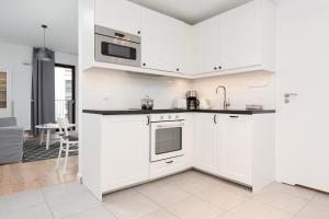 una cocina blanca con armarios y electrodomésticos blancos en Apartments Westfield Arkadia Burakowska by Renters, en Varsovia
