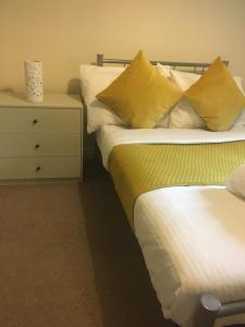 a bedroom with two beds with yellow pillows and a dresser at global relocation 2 Bed Apt Near Hatfield Station Free Parking in Hatfield