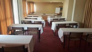 une rangée de tables et de chaises dans une pièce avec des tables blanches dans l'établissement London Class Hotéis, à São Paulo