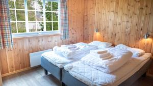 a bed in a wooden room with towels on it at Geilolia Hyttetun in Geilo