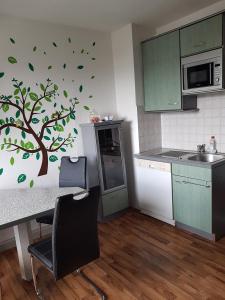 uma cozinha com um mural de árvore na parede em Ferienwohnung "Am Vaterlandsgrubenweg" - a57586 em Oelsnitz