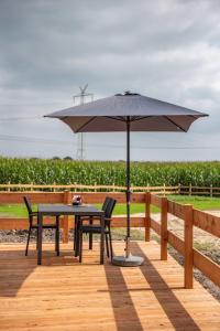 a table and chairs under an umbrella on a wooden deck at Huxfeld-Hof - Tiny-House KUHni in Grasberg