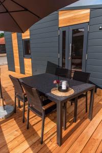 a black table and chairs on a deck at Huxfeld-Hof - Tiny-House KUHni in Grasberg