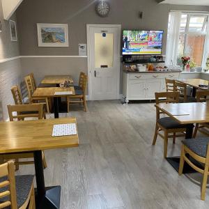 a restaurant with tables and chairs and a flat screen tv at Inglewood Guest House in Sandown