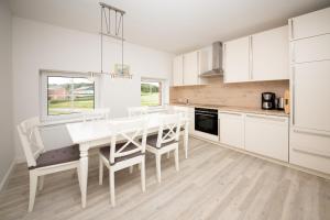 Rabenkirchen-FaulückにあるSchleiblick Familienappartement 13の白いキャビネット、テーブルと椅子付きのキッチンが備わります。